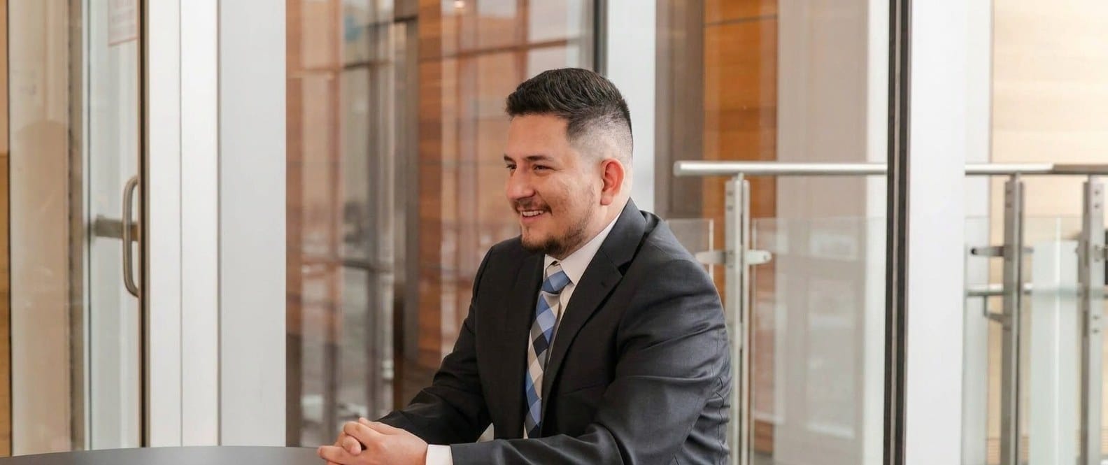 Mosiah Olvera seated at a conference table by a glass office wall, listening during a client meeting