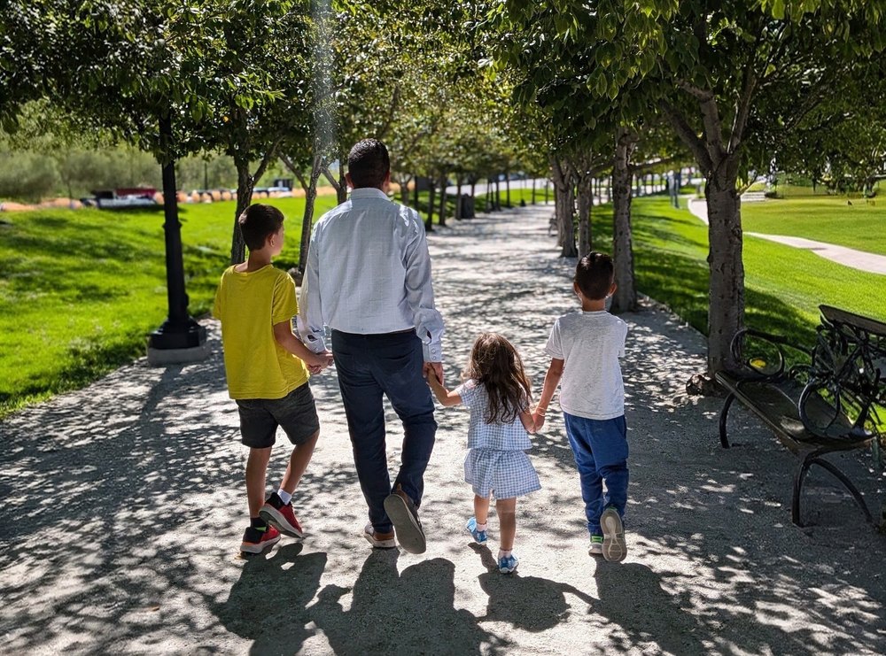 Mosiah Olvera walking hand in hand with three children along a tree-lined path